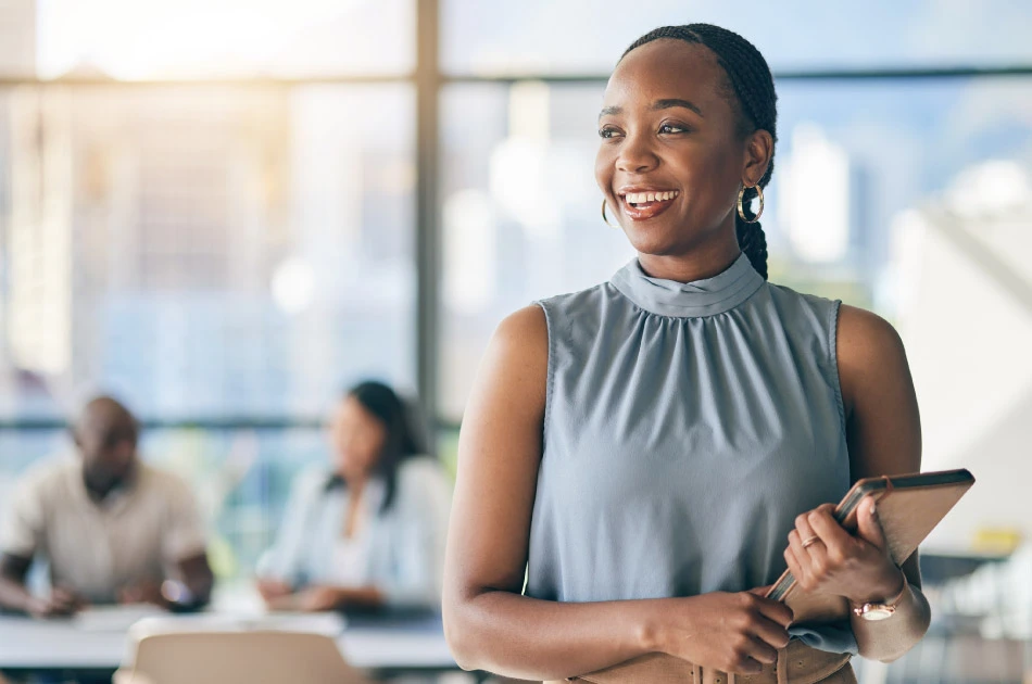 Black woman in office leadership meeting smiling and holding tablet