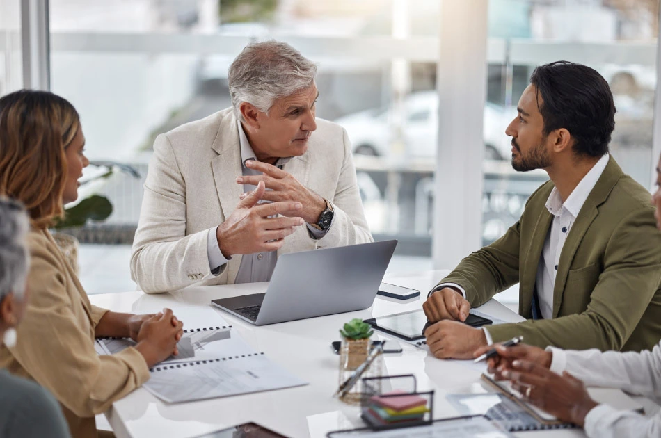 Businessman with laptop and team with documents in meeting for strategy planning at office