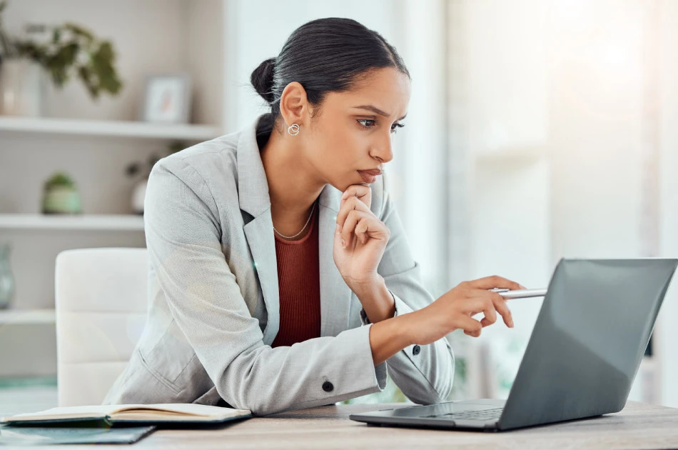 Serious, laptop and professional businesswoman sitting and reading a work email with a pen working from home